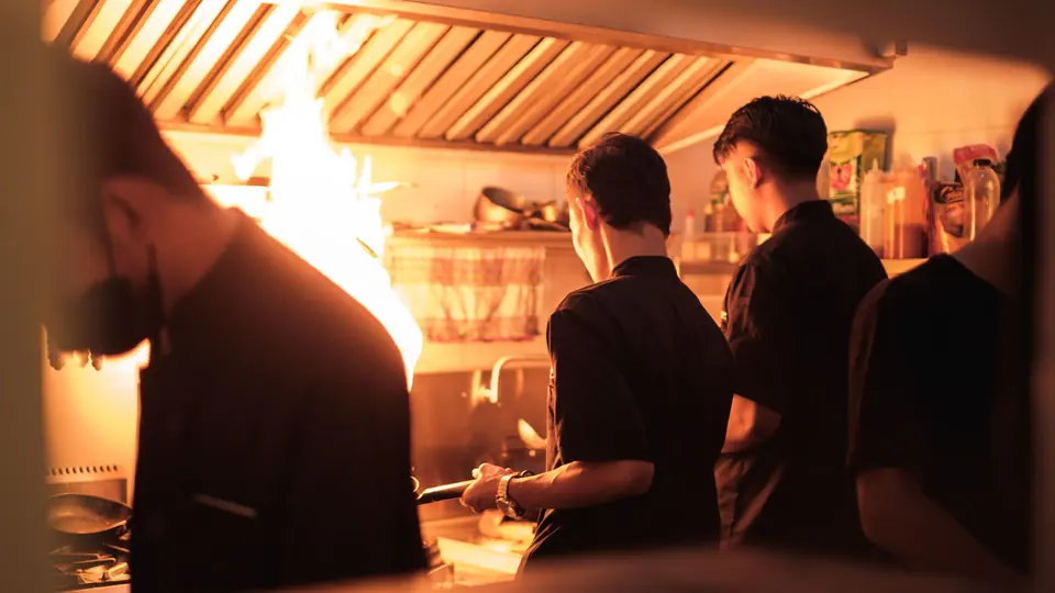 Köche arbeiten am Abend an der Flamme in einer Restaurantküche