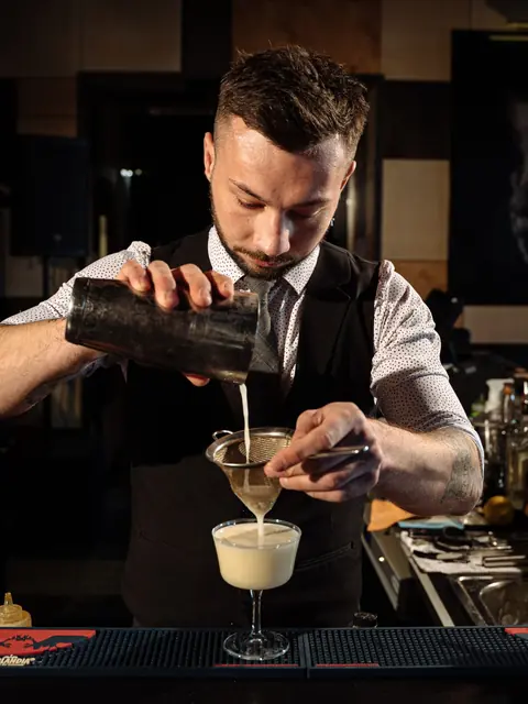 Barkeeper gießt einen Cocktail an der Bar