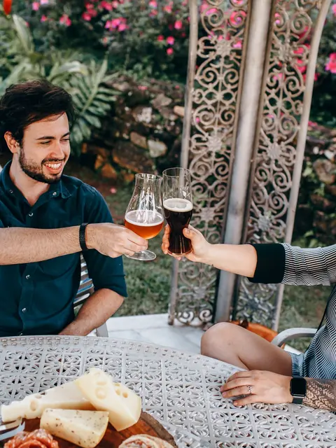 Zwei Gäste stoßen im Biergarten mit Bier an