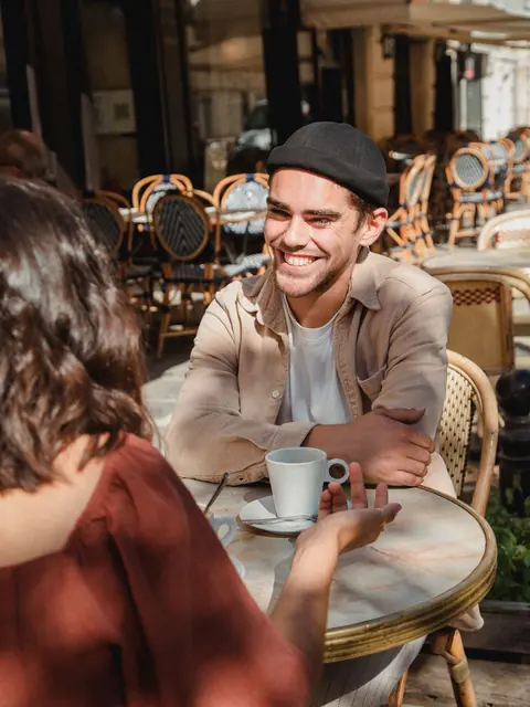 Lachender Gast mit Kaffee auf einer Café-Terrasse